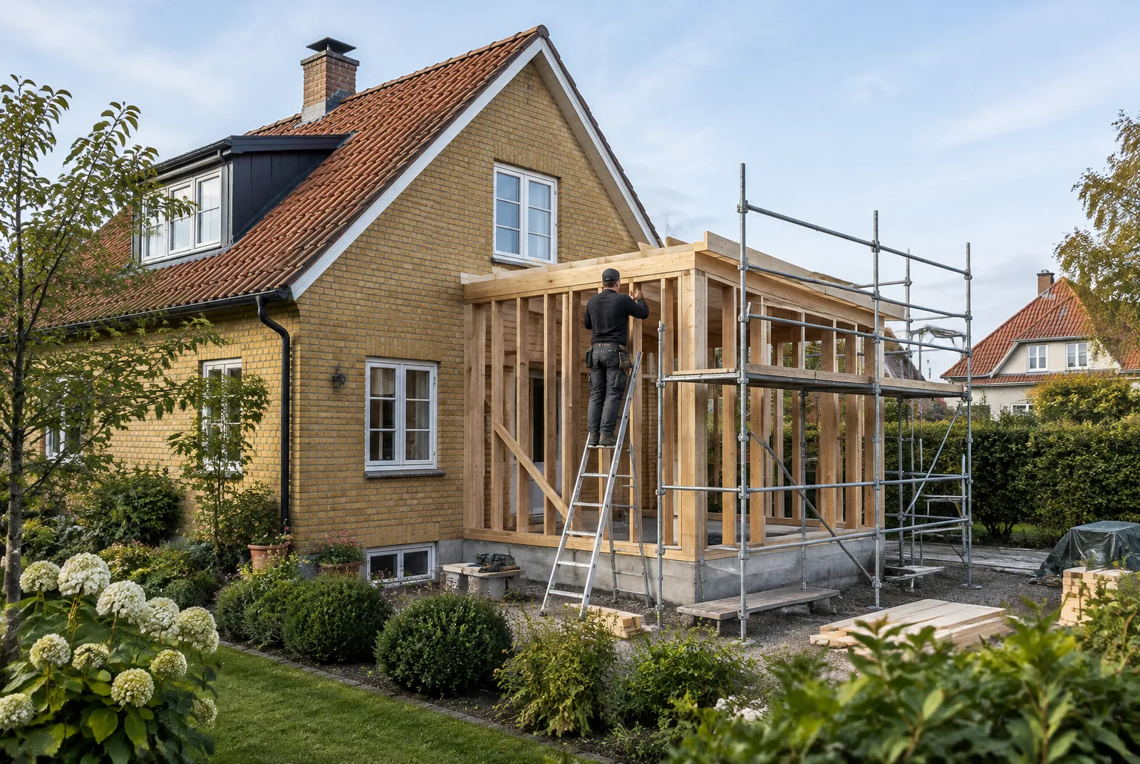Skånsk villa i gult tegel med en ny tillbyggnad i trästomme under uppförande